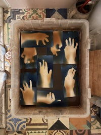 a box filled with hand prints on a tiled floor